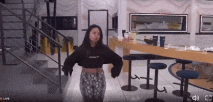 a woman in a black hoodie is dancing in a room with stools and stairs