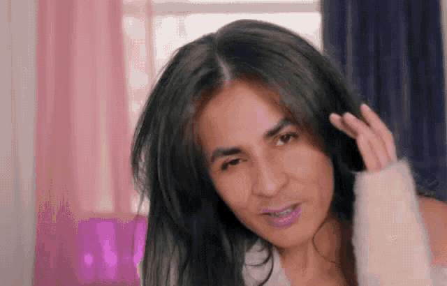 a woman with long black hair is looking at the camera while holding her hair .