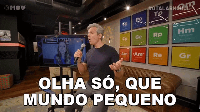 a man singing into a microphone with the words olha so que mundo pequeno