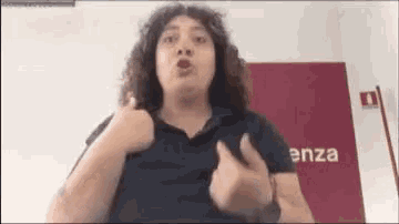 a woman with curly hair is giving a thumbs up in a room .