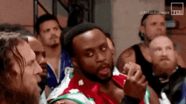 a group of wrestlers are standing around each other in a ring .