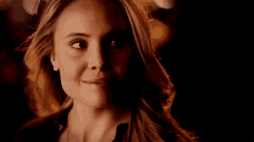 a woman is smiling with her eyes closed in a dark room .