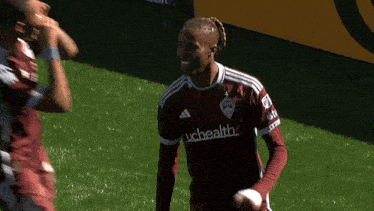 a soccer player wearing a uchealth jersey stands on the field