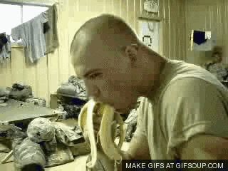 a man is eating a banana in a room with a make gifs at gifsoup.com watermark