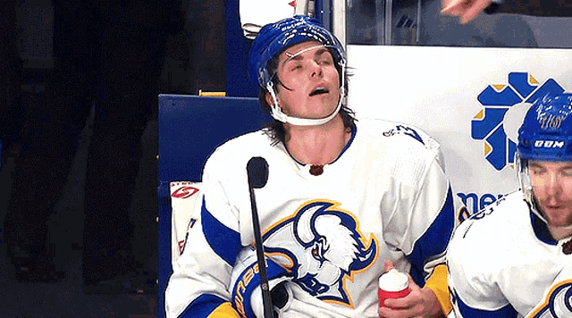 a hockey player wearing a sabres jersey holds a cup