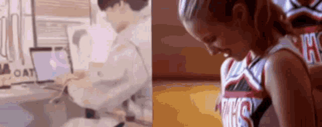 a cheerleader is kneeling down next to a doctor using a laptop .