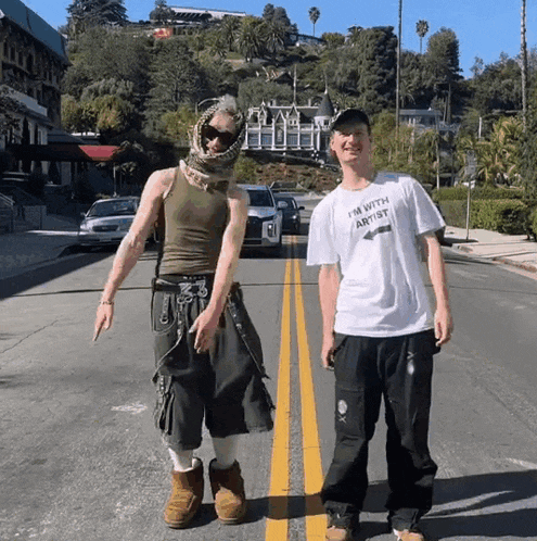 a man wearing a t-shirt that says " i 'm with artist " stands next to another man