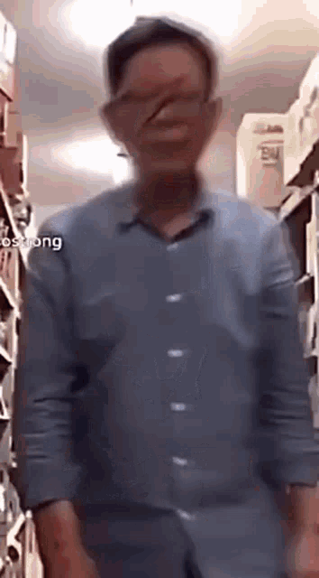 a man in a blue shirt is standing in a store with his eyes closed .
