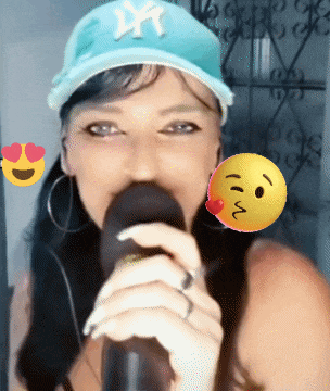 a woman singing into a microphone with a ny hat on