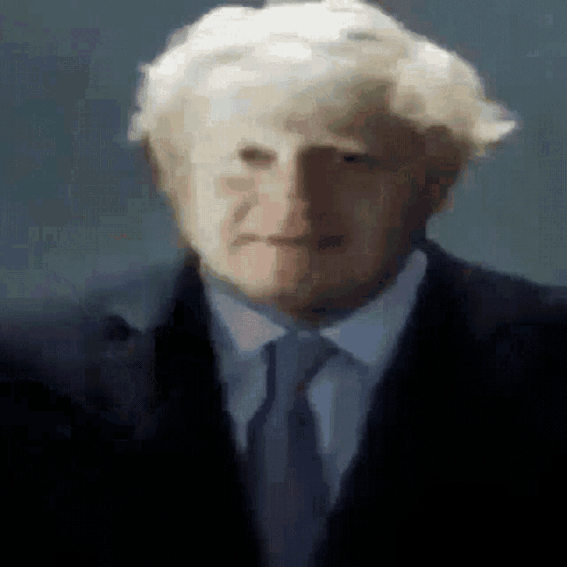 a close up of a man in a suit and tie looking at the camera