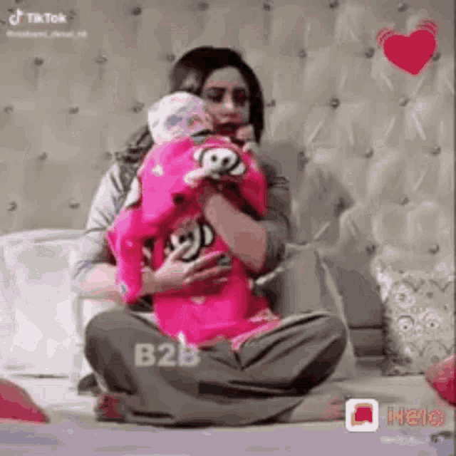 a woman is sitting on the floor holding a baby in her arms .