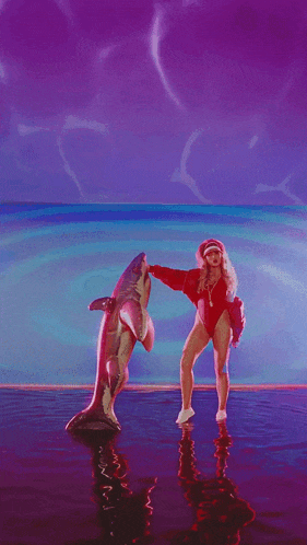 a woman in a red swimsuit is dancing with a shark in the water