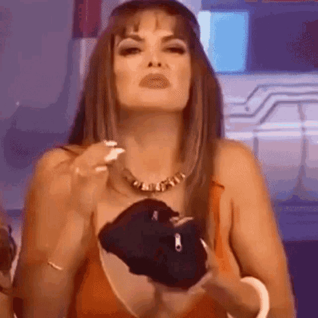 a woman in a bikini is holding a black object in her hand and making a funny face .