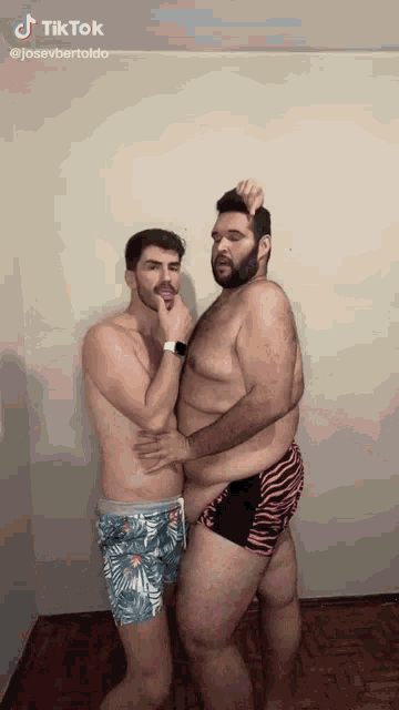 two shirtless men are standing next to each other and one of them has a large belly