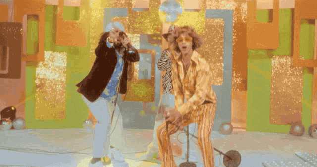 a group of people dressed in fancy costumes are singing into microphones on a stage