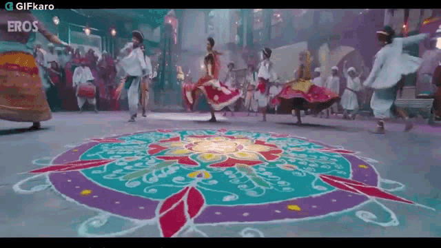 a group of people are dancing in front of a colorful mandala
