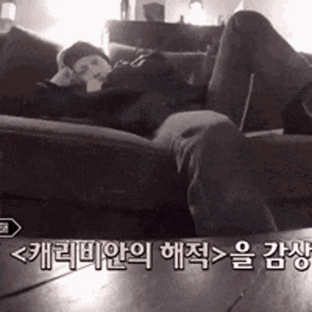 a person laying on a couch with korean writing on the floor behind them
