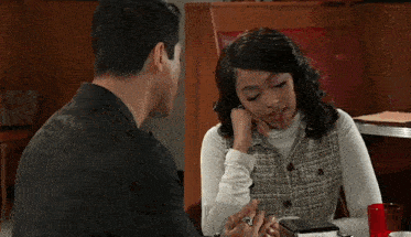 a man and a woman are sitting at a table in a diner with their eyes closed
