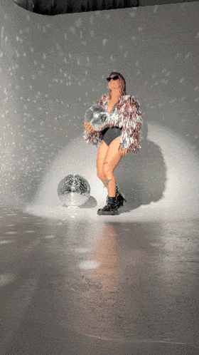 a woman is holding a disco ball and standing next to it