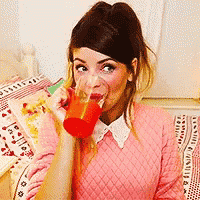 a woman wearing a pink sweater is drinking from a red cup