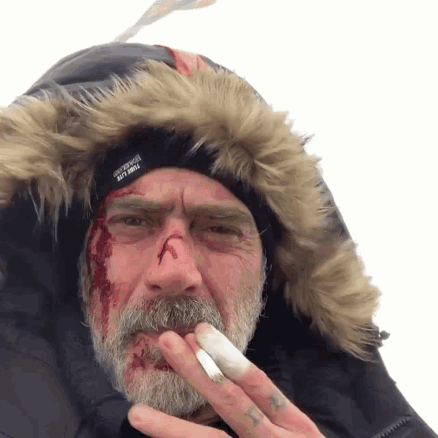 a man with a beard wearing a fur hooded jacket and a gray hat that says " survival " on it