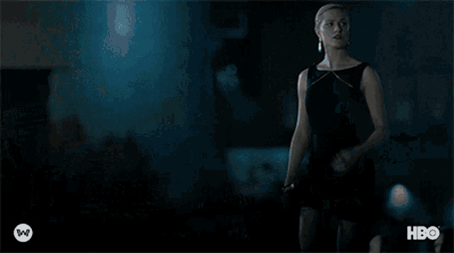 a woman in a gold dress is standing in front of a man in a suit and hbo logo