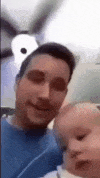a man is holding a baby and wearing a snoopy hat .