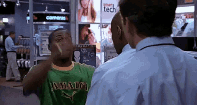 a man wearing a jamaica shirt is talking to another man in a store