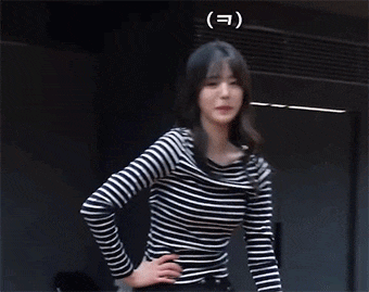 a woman wearing a black and white striped shirt is standing in a dark room ..