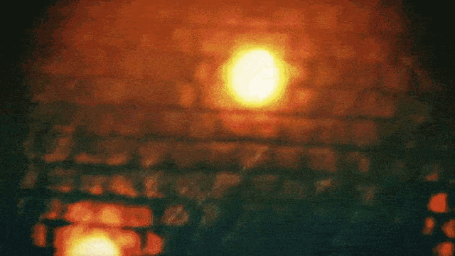 a blurry picture of a person standing in front of a brick wall with a yellow light in the background