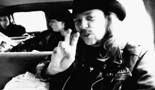 a man in a cowboy hat is sitting in the back seat of a car giving a peace sign .