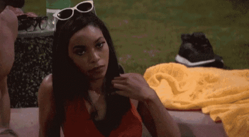 a woman wearing sunglasses and a red top is sitting on a couch .
