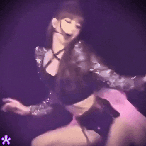 a woman in a black top and pink shorts is dancing on stage