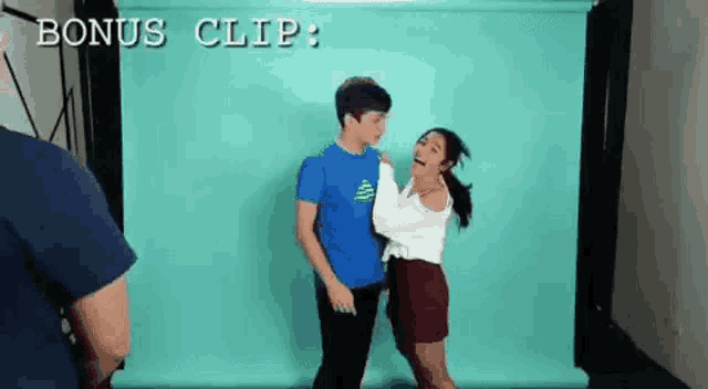 a boy and a girl are standing next to each other in front of a blue background .
