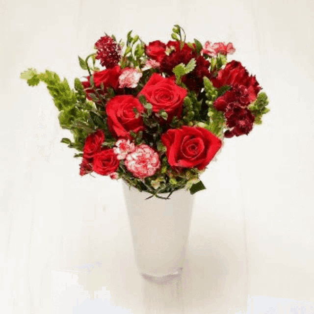 a vase filled with red roses and other flowers