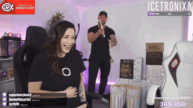 a woman laughs while a man holds a bottle of champagne in front of a sign that says icetronix on it