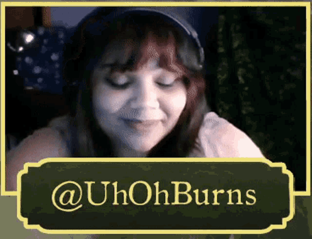 a woman wearing headphones and a hat is behind a sign that says @uh oh burns