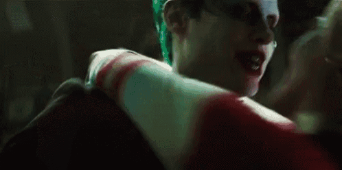 a man in a joker costume is kissing a woman in a suicide squad costume .