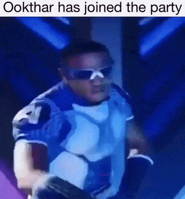 a man wearing sunglasses and a blue shirt is dancing in a dark room with the caption " ookthar has joined the party " .