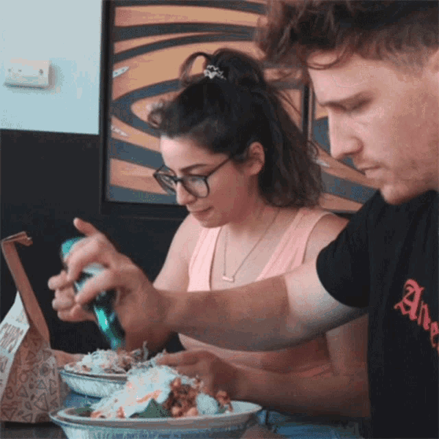 a man and a woman are sitting at a table eating a meal