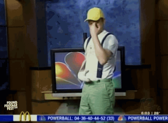 a man in a yellow hat is covering his face in front of a mcdonald 's sign