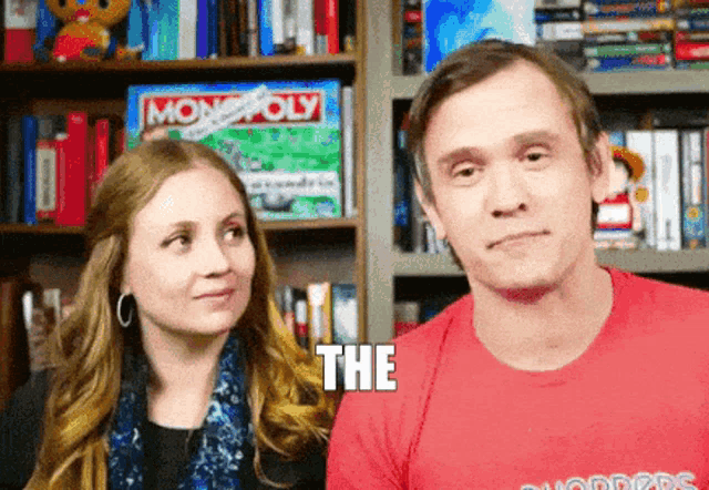 a man and a woman are looking at each other and the man is wearing a red shirt that says the
