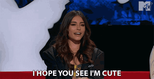 a woman says " i hope you see i 'm cute " while sitting in front of a mtv logo