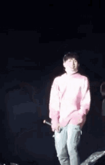 a man is standing on a stage holding a microphone .