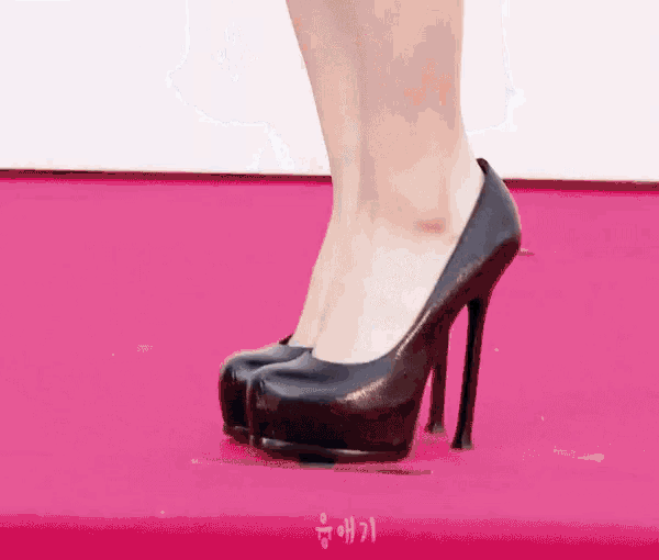 a close up of a woman 's feet wearing black high heels on a red carpet .