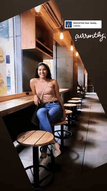a woman sits on a wooden stool in a restaurant with a sign that says rockstar on it