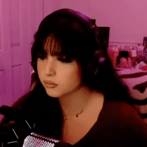 a woman wearing headphones and a necklace is sitting in front of a microphone in a room .