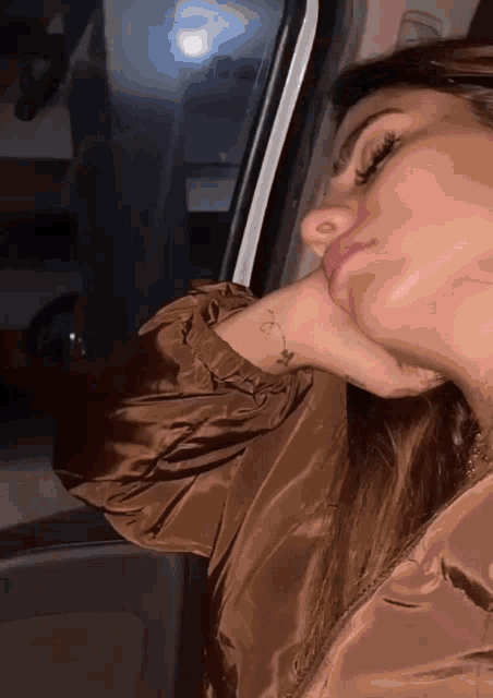a woman with a tattoo on her wrist looks out the window of a car