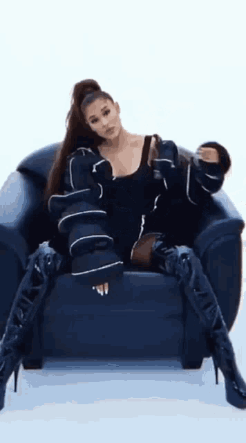 ariana grande is sitting in a chair wearing black boots and a black jacket .