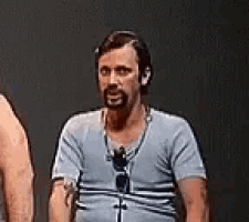 a man with a beard and sunglasses is standing next to two other men .